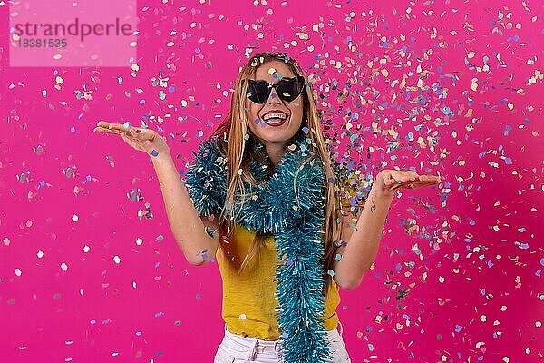 Kaukasisches Mädchen  das in der Disco feiert und lachend Konfetti wirft  vor einem rosa Hintergrund