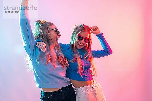 Zwei junge blonde kaukasische Frauen tanzen in der Disco  lächelnd und mit Spaß auf der Party