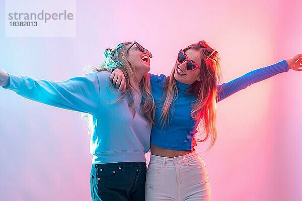 Zwei junge blonde kaukasische Frauen tanzen in der Disco  lächelnd und mit Spaß