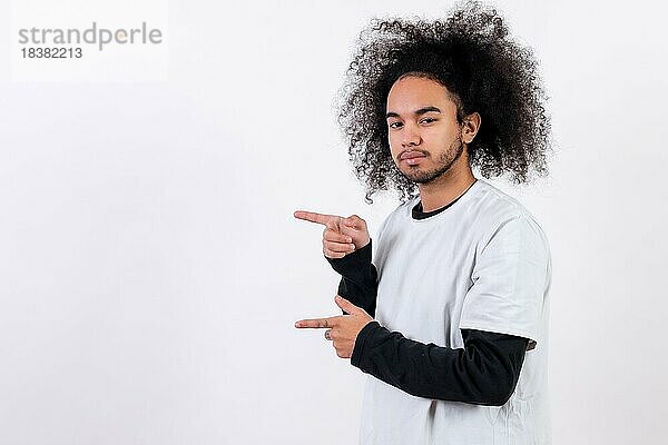 Zeigt nach links auf einen Copy Paste Platz. Junger Mann mit Afro Haar auf weißem Hintergrund