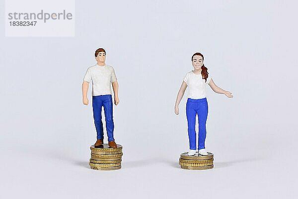 Konzept des geschlechtsspezifischen Lohngefälles mit einem Mann und einer Frau  die auf einer unterschiedlichen Anzahl von Münzen stehen