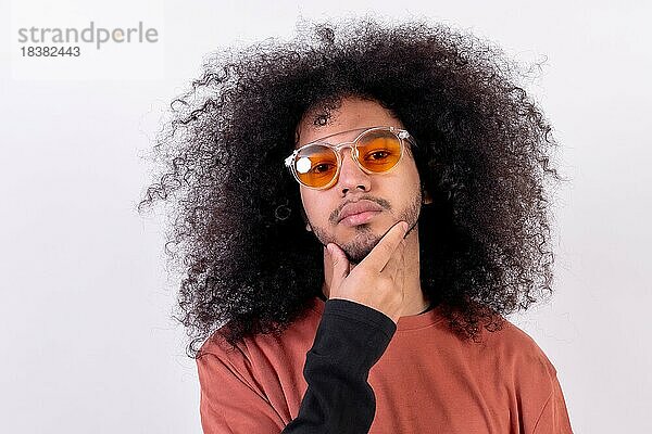 Portrait mit Sonnenbrille und verführerischem Blick. Junger Mann mit Afro Haar auf weißem Hintergrund