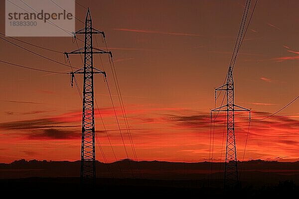 Silhouette von Hochspannungsleitungen und Sendemasten durch das Mährische Feld bei Sonnenaufgang