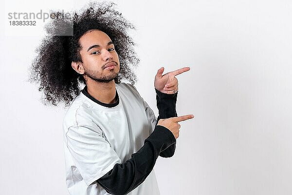 Zeigt nach rechts auf einen Copy Paste Platz. Junger Mann mit Afro Haar auf weißem Hintergrund