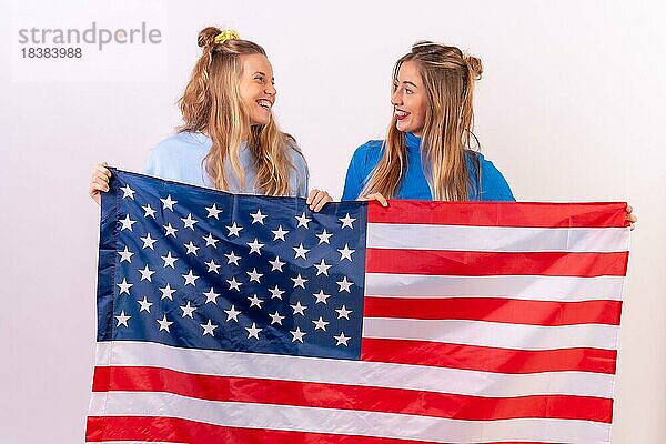 Zwei junge blonde kaukasische amerikanische Flagge  Porträt lächelnd  vor einem weißen Hintergrund