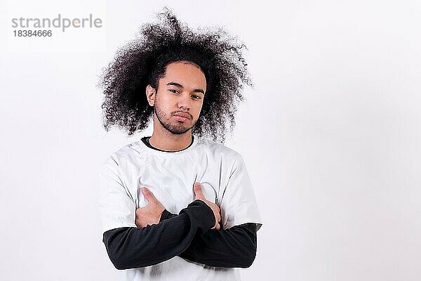 Porträt mit verschränkten Armen und Blick. Junger Mann mit Afro Haar auf weißem Hintergrund