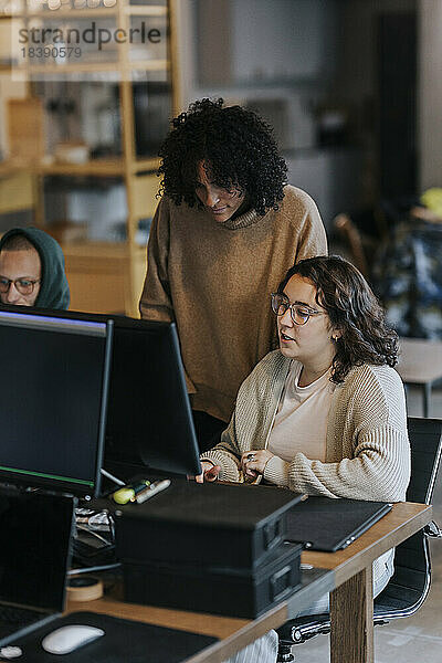 Multirassische Geschäftskollegen diskutieren über Computer am Schreibtisch im Büro