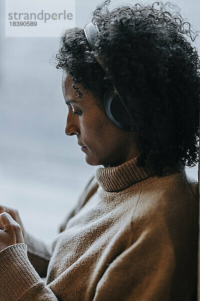 Seitenansicht einer Geschäftsfrau  die über drahtlose Kopfhörer im Büro Musik hört