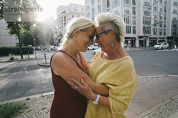 Zwei ältere Frauen umarmen sich auf der Straße in der Stadt