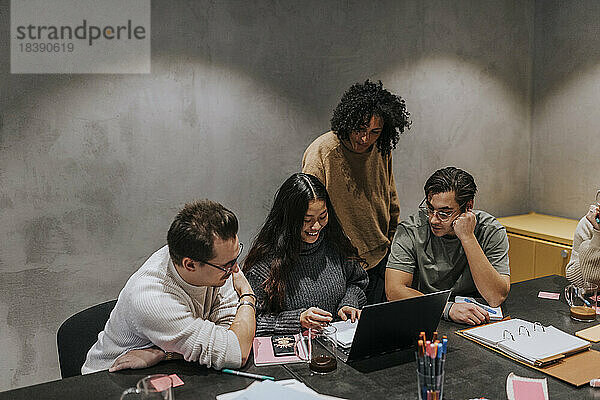 Multirassische männliche und weibliche Kollegen diskutieren über Laptop am Konferenztisch im Büro