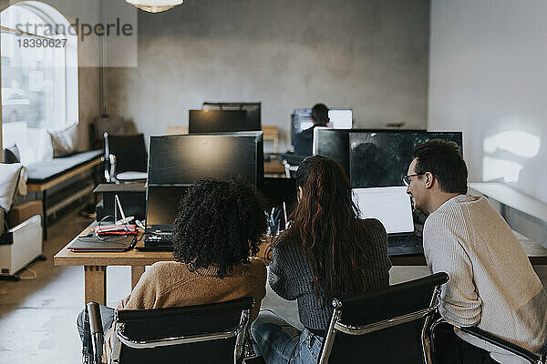 Rückansicht von multirassischen Computerprogrammierern  die am Schreibtisch in einem kreativen Büro diskutieren