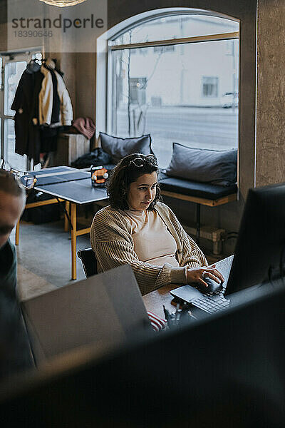 Junge Hackerinnen arbeiten am Laptop eines männlichen Kollegen in einem Start-up-Unternehmen