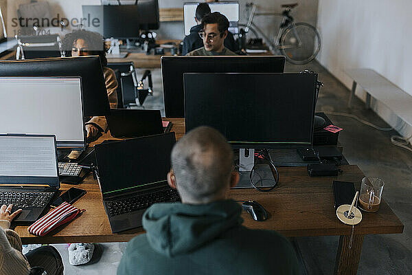 Männliche und weibliche Computerprogrammierer  die in einem Start-up-Unternehmen am Schreibtisch arbeiten