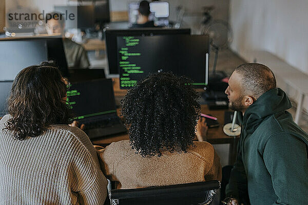 Multirassische Hackerinnen und Hacker beim Programmieren am Computer während der Arbeit an einem kreativen Arbeitsplatz