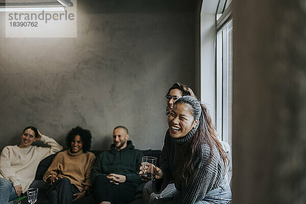 Fröhliche Geschäftsfrau  die mit ihren Kollegen Kaffee trinkt  während sie eine Pause in einem Start-up-Unternehmen macht