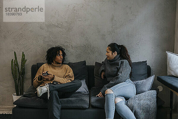 Geschäftsfrau diskutiert mit einer auf dem Sofa sitzenden Kollegin in einem Start-up-Unternehmen