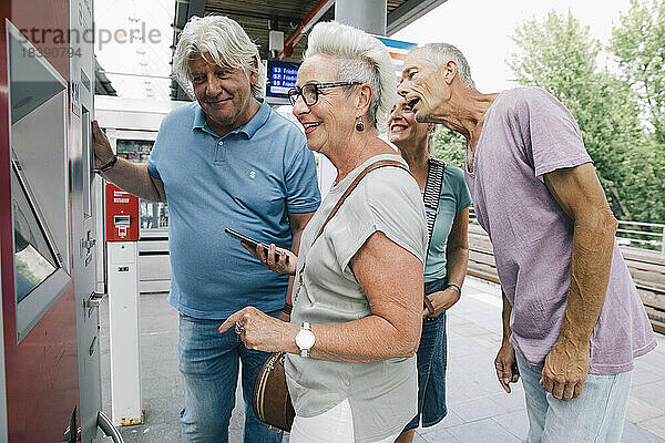 Gruppe älterer Freunde  die auf dem Bahnsteig eine Fahrkarte kaufen