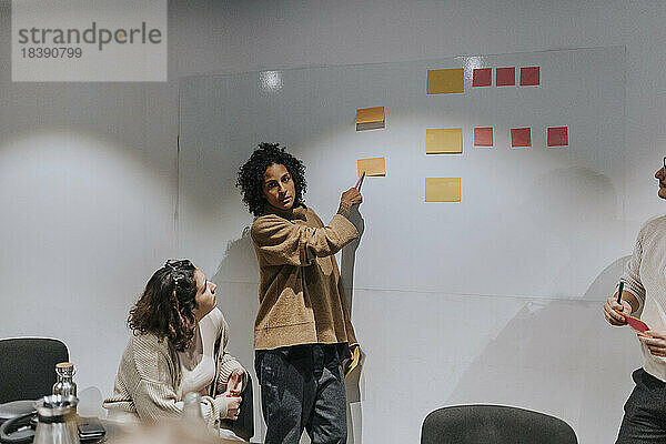 Eine Unternehmerin erklärt ihren Kollegen in einer Sitzung im Sitzungssaal die Geschäftsstrategie