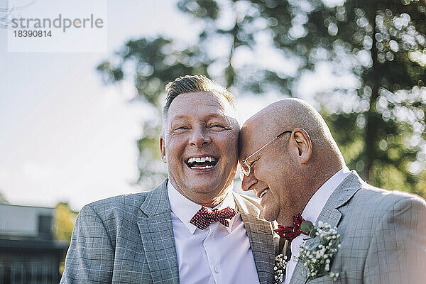 Fröhliches  frisch verheiratetes schwules Paar lacht zusammen bei der Hochzeit