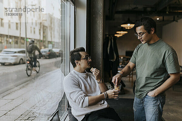 Geschäftsmann im Gespräch mit einem männlichen Kollegen bei einem Keks in der Pause in einem Start-up-Unternehmen