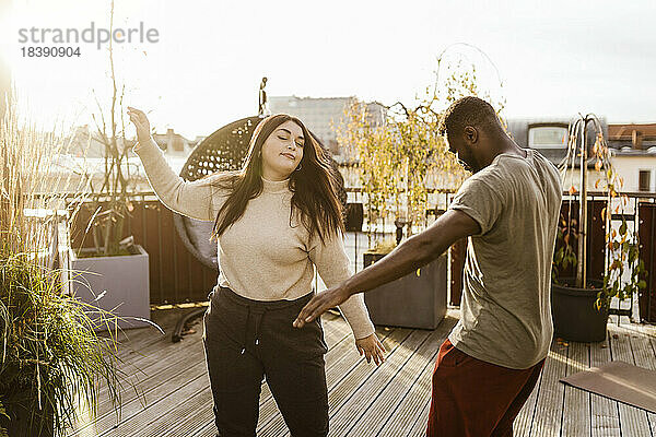 Unbeschwerter Mann und Frau tanzen zusammen auf der Terrasse