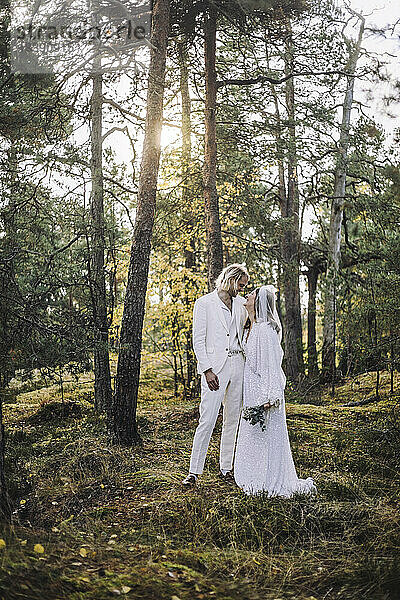 In voller Länge von frisch verheirateten Paar stehen durch Bäume im Wald während der Hochzeit