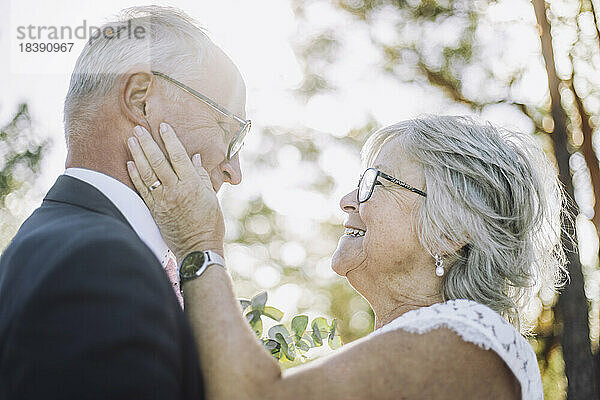 Lächelnde  liebevolle ältere Braut berührt die Wange des Bräutigams