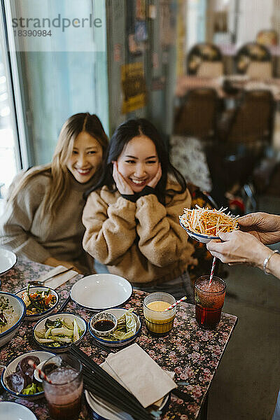 Glückliche Freundinnen betrachten das Essen in einem Restaurant