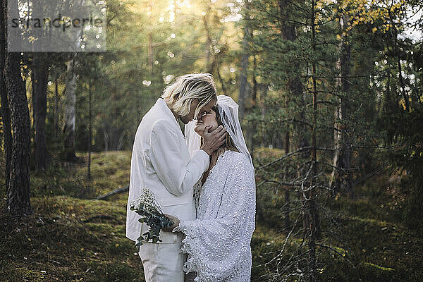 Frisch verheiratetes Paar küsst sich am Hochzeitstag im Wald