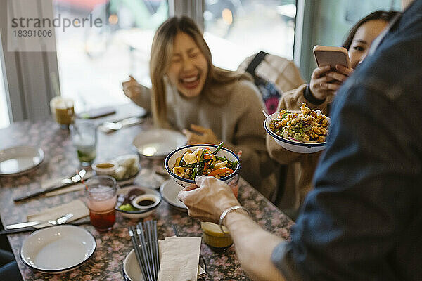 Kellner serviert chinesisches Essen an Kunden im Restaurant