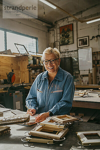 Porträt einer glücklichen älteren Schreinerin in einer Werkstatt