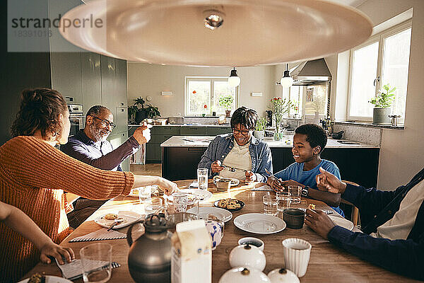 Eine Mehrgenerationen-Familie  die gemeinsam das Essen auf dem Esstisch zu Hause genießt