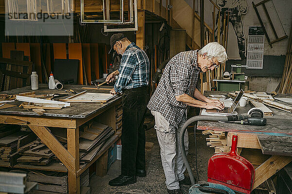 Ältere Handwerker arbeiten in der Schreinerei zusammen