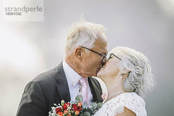 Zärtliches älteres Paar küsst sich auf den Mund gegen die Wand
