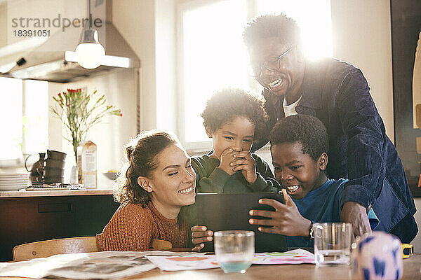 Glückliche Familie  die Spaß hat  während sie zu Hause gemeinsam ein digitales Tablet betrachtet