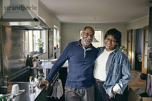 Porträt eines glücklichen älteren Paares  das zusammen in der Küche zu Hause steht