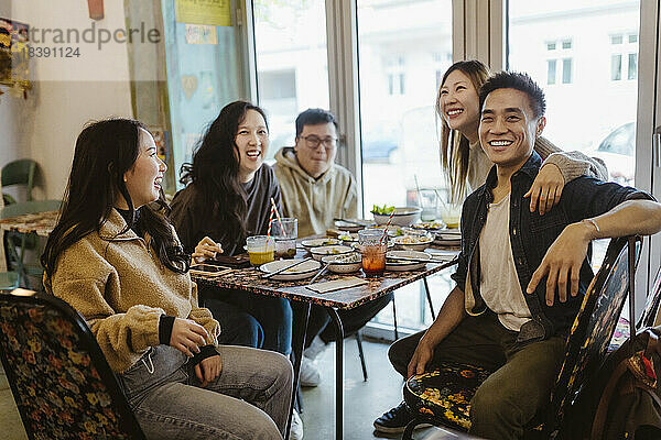 Glückliche männliche und weibliche Freunde genießen gemeinsam das Mittagessen im Restaurant