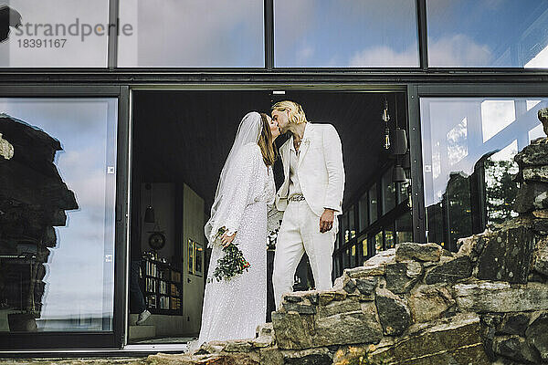 Affectionate Mitte erwachsenen Paar küssen auf Mund von Eingangshalle während Hochzeitstag