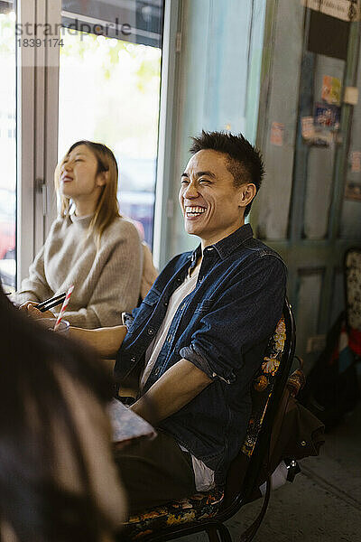 Mann lacht  während er mit einer Freundin im Restaurant sitzt
