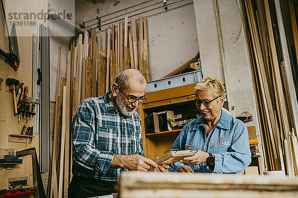 Männliche und weibliche Senior-Unternehmer diskutieren in einer Werkstatt über einen Rahmen