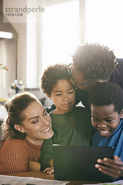 Glückliche gemischtrassige Familie  die sich zu Hause vor dem digitalen Tablet amüsiert