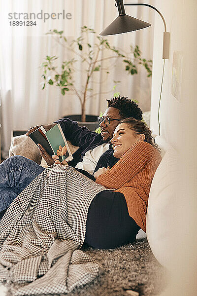 Mann und Frau lesen Bücher  während sie zu Hause auf dem Sofa sitzen