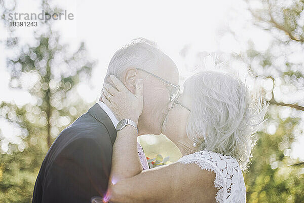Romantische frisch verheiratete ältere Braut küsst Bräutigam auf den Mund bei der Hochzeit während des sonnigen Tages