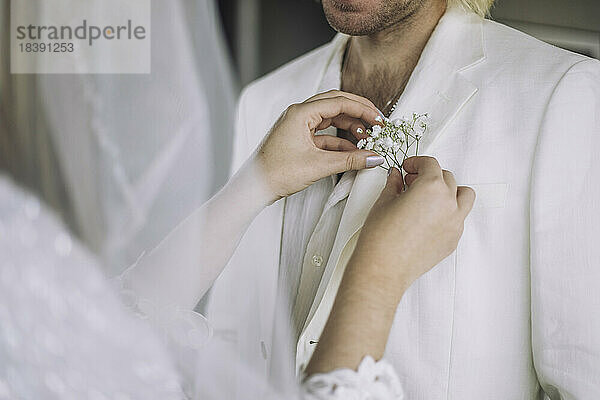 Mittelteil der Braut bei der Anpassung der Boutonniere in der Tasche des Bräutigams bei der Hochzeit