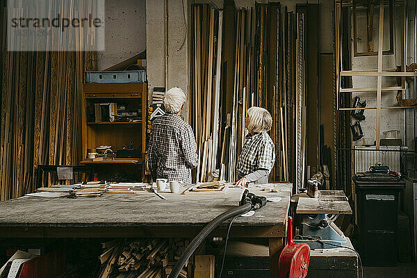 Männliche und weibliche Senior-Unternehmer begutachten Holz in der Werkstatt