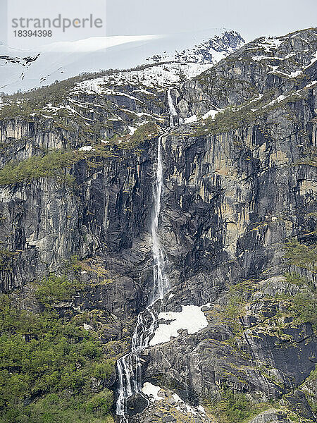Blick auf einen Wasserfall an einer steilen Bergwand mit dem Myklebustbreen-Gletscher an der Spitze  Vestland  Norwegen  Skandinavien  Europa