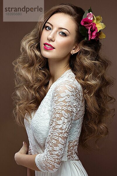 Schöne blonde Frau im Hochzeitskleid mit Abendmakeup zarten Lippen und Locken. Bild einer Braut. Schönheit Gesicht. Bild im Studio auf einem grauen Hintergrund genommen