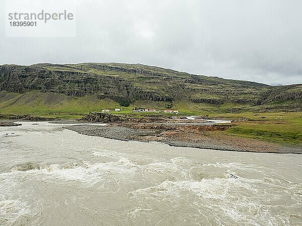 Gletscherfluss und Bauernhof vor Bergmassiv  bei Höfn  Ostfjorde  Island  Europa