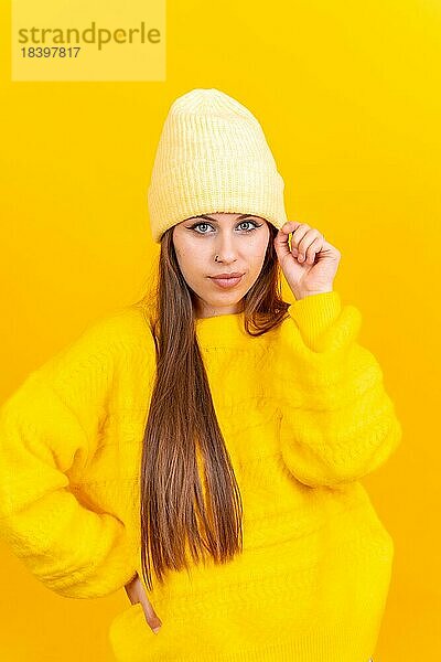 Close up Porträt einer jungen kaukasischen Frau in Wollpullover vor gelbem Hintergrund  lächelnd