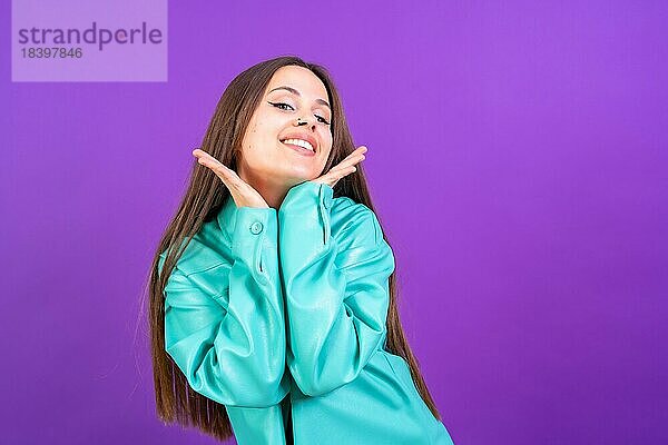 Close up Porträt einer jungen Frau  fröhlich oder lachend vorlila Studio Hintergrund in blauen Windbreaker